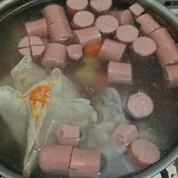 Setelah wortel empuk, masukkan sosis dan siomay, tambahkan minyak wijen, garam, gula, dan kaldu bubuk.