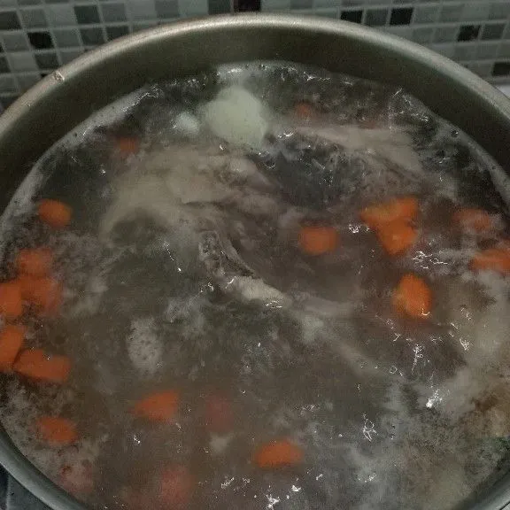 Didihkan air, masukkan bawang putih, jahe, dan tulang ayam. Setelah kaldu keluar, masukkan wortel.