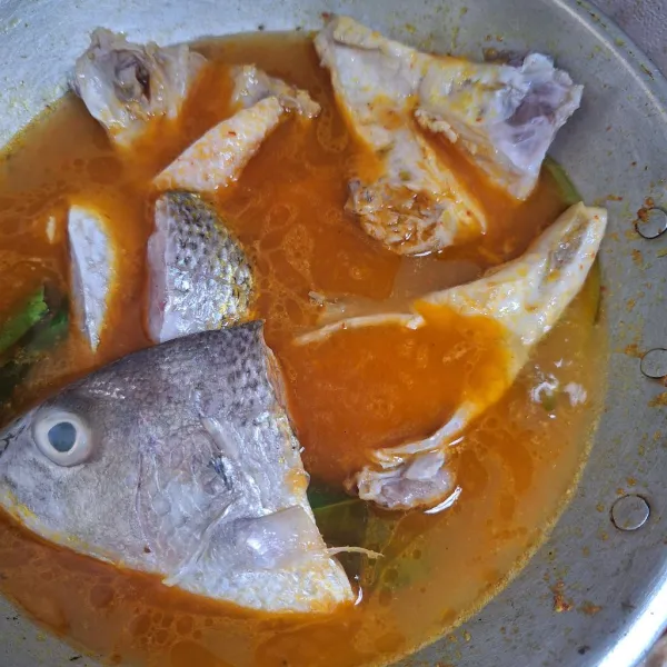 Setelah air mendidih, masukkan ikan yang sudah dimarinasi, tutup wajan, masak sebentar