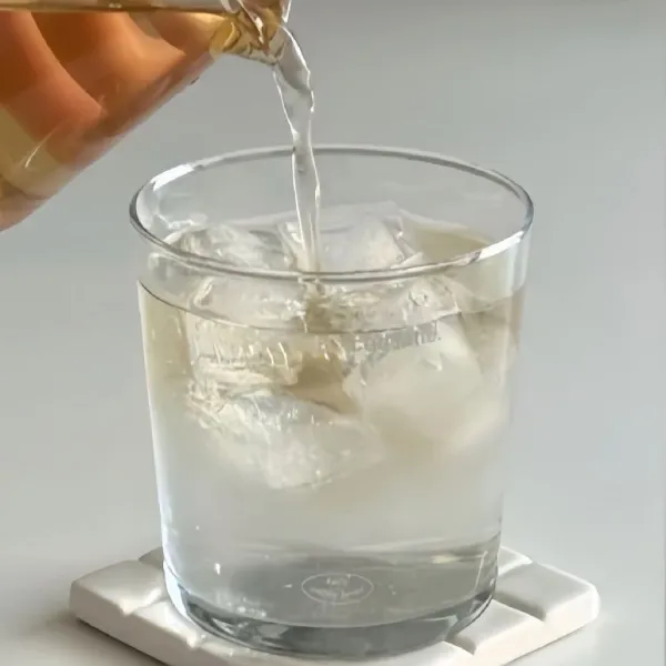 Tambahkan 200 ml teh pu-erh yang sudah disaring ke dalam gelas berisi air kelapa