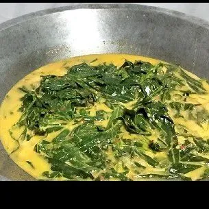 Masukkan daun singkong setelah santan mulai mendidih.