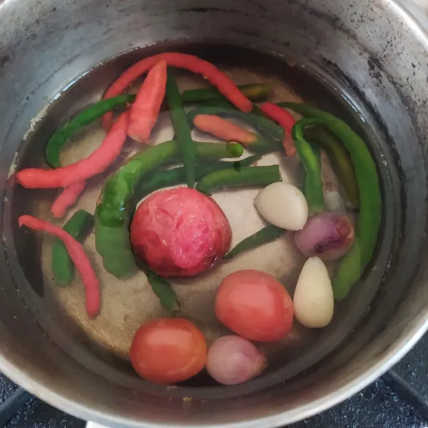 Didihkan secukupnya air, rebus bawang merah, bawang putih, cabai dan tomat hingga 1/2 matang. Gunakan api sedang.