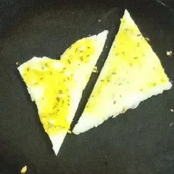 Oles kedua sisi roti tawar dengan campuran margarin tadi. Panaskan teflon, tidak perlu diolesi margarin. Lalu panggang roti tawar hingga kecoklatan, bolak-balik supaya matang merata.