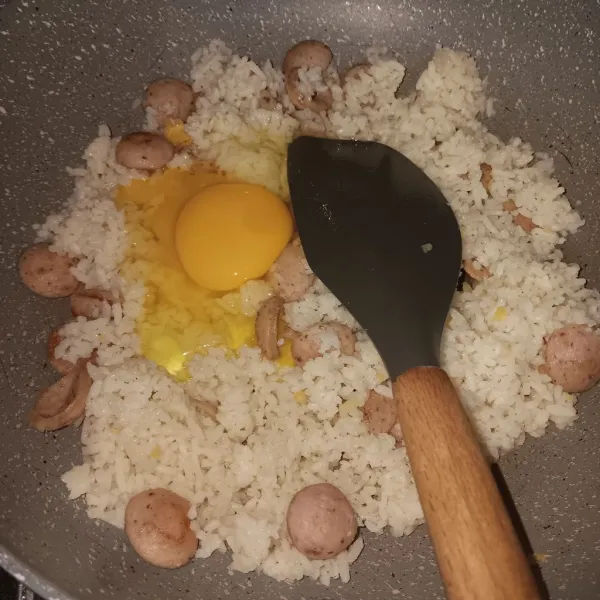 Set api sampai hampir sedang. Pecahkan telur kemudian aduk sampai menyatu dengan nasi, aduk terus sampai kembali berbulir.