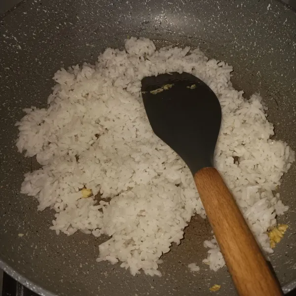 Masukkan nasi, lalu aduk sampai tercampur rata. Masih menggunakan api kecil, karena kita bukan mau bikin nasi goreng.