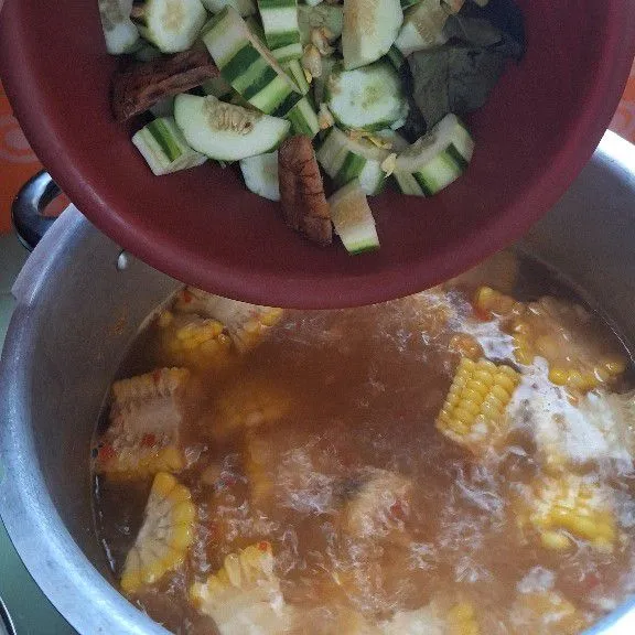 Setelah jagung sudah empuk, masukkan krai (mentimun), labu siam, laos, daun salam, masak hingga empuk.