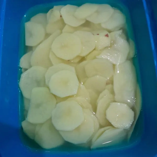 Kupas kentang dari kulitnya lalu iris tipis-tipis