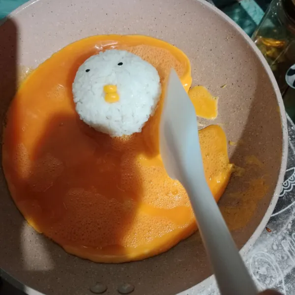 Panaskan wajan yang sudah dioles tipis minyak. Masukkan telur kocok, tunggu 30 detik masukkan nasi kepal. Pakai api sedang cenderung kecil.