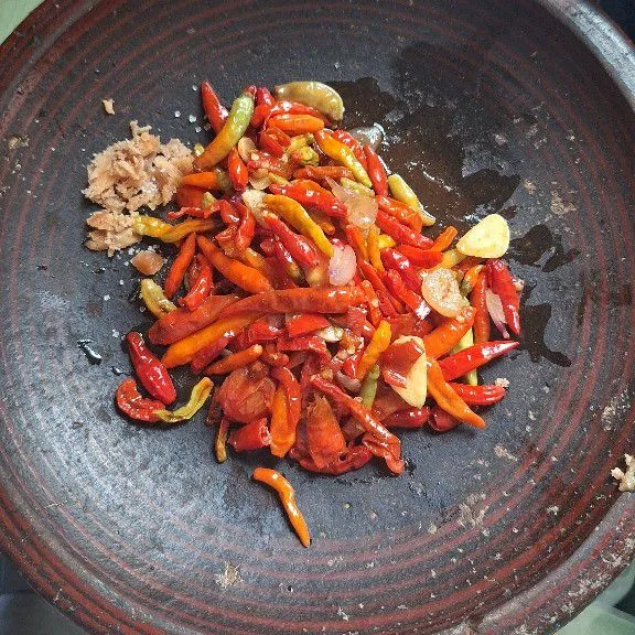 Tumis cabe rawit, cabe merah, bawang merah, bawang putih, lalu pindahkan ke cobek dan tambahkan gula, garam, gula merah.