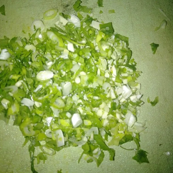 Cincang bawang putih dan daun bawang.