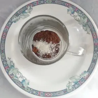 Siapkan gelas, kemudian tambahkan kopi bubuk dan gula pasir.