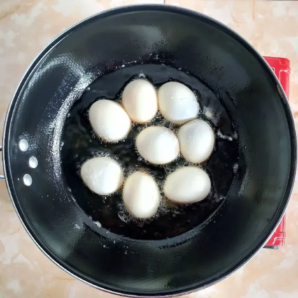 Panaskan secukupnya minyak goreng, kemudian goreng telur rebus hingga berkulit. Angkat dan tiriskan.