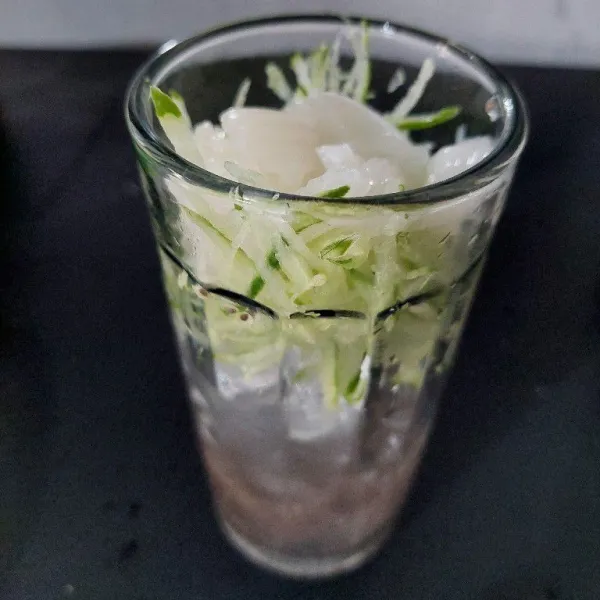 Siapkan gelas saji, masukkan es batu, biji selasih yang sudah direndam, timun serut dan jeli.