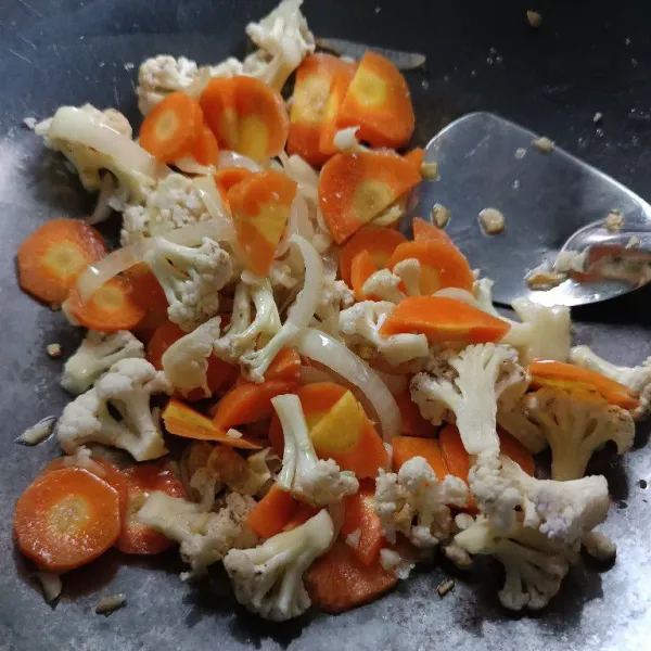 Masukkan wortel dan kembang kol. Aduk rata. Tumis hingga setengah matang.