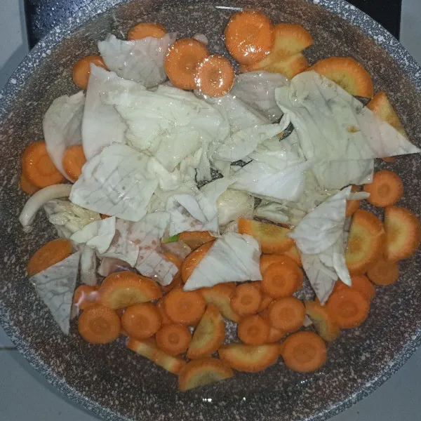 Masukkan 900 ml air ke dalam panci, tunggu mendidih. Masukkan wortel, kentang, dan kubis. Tutup panci dan tunggu beberapa menit.