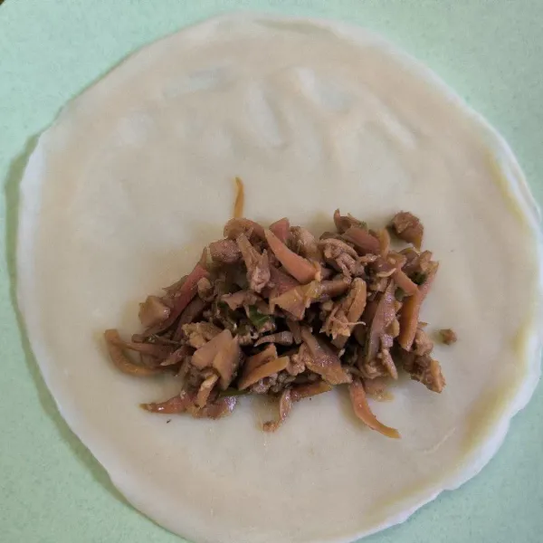 Ambil satu lembar kulit lumpia tambahkan bahan isian secukupnya kemudian lipat bentuk amplop lalu gulung.