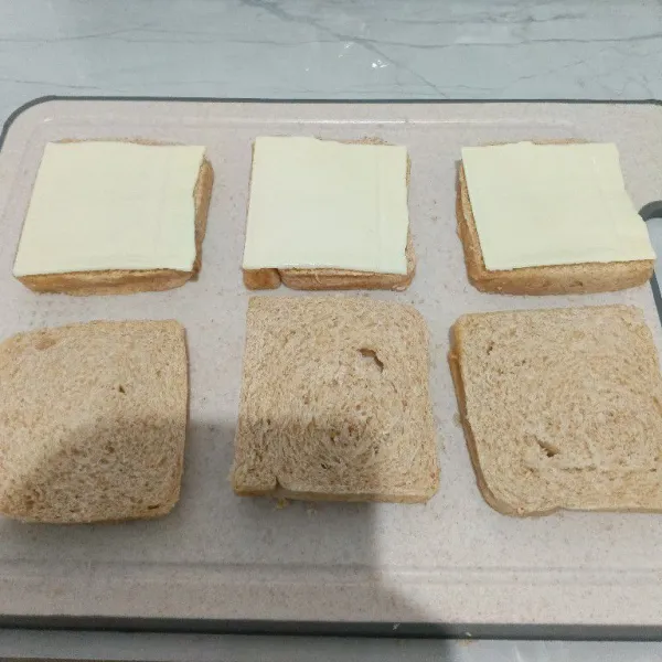 Tambahkan keju slice diatas permukaan roti.