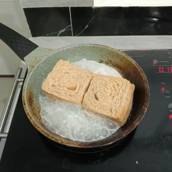 Masukkan roti ke dalam campuran susu. Kemudian balik sisi roti yang lainnya.