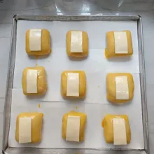 Tambahkan potongan keju slice. Olesi kembali dengan bahan olesan. Panggang dalam oven suhu 170°C selama 25 menit api atas bawah atau sampai matang.