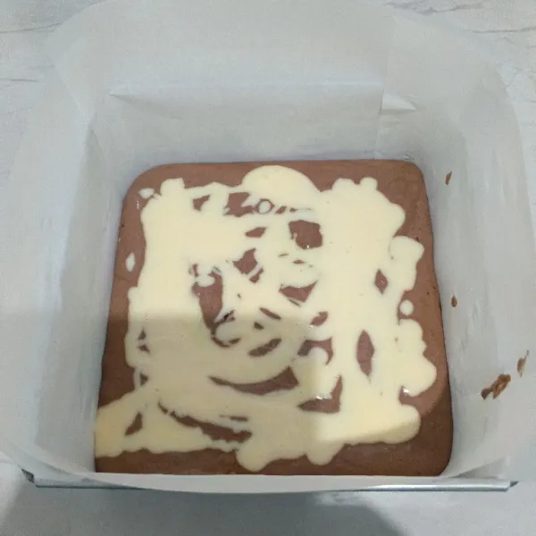 Kemudian tuang adonan cream cheese diatas adonan coklat. Lalu tuang kembali sisa adonan coklatnya.