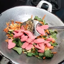 Langkah kelima masukkan wortel yang sudah di iris tipis lalu masak hingga layu setelah itu baru masukkan sawi hijau, dan juga sosis masak hingga tercampur rata.