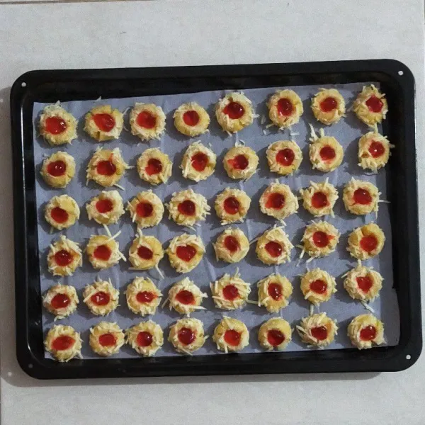Tata dalam loyang yang telah di oles margarin dan baking paper,tekan tengahnya dengan jari sehingga membentuk cekungan, kemudian semprotkan selai strawberry.