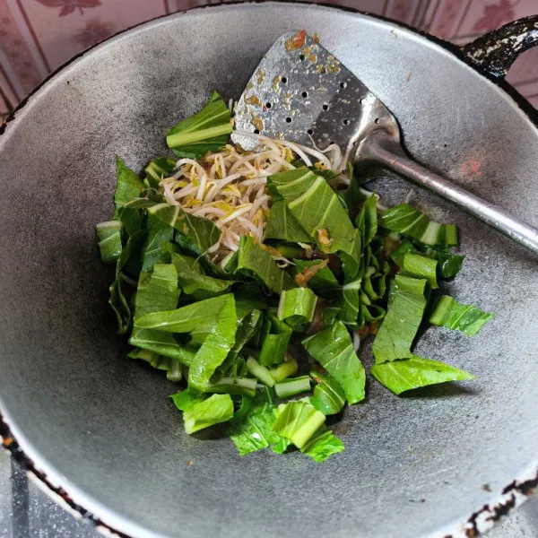 Setelah bumbu matang masukkan sawi dan tauge aduk rata.