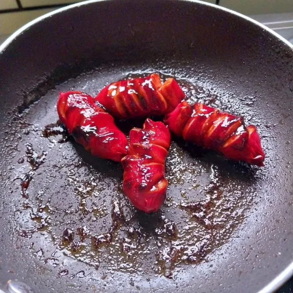 Panggang sosis di atas teflon sampa matang.
