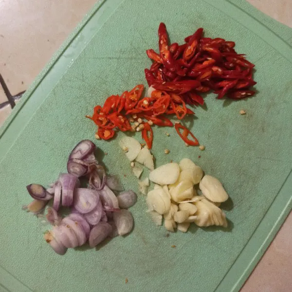 Iris tipis bawang putih, bawang merah, cabe merah besar, dan cabe rawit.