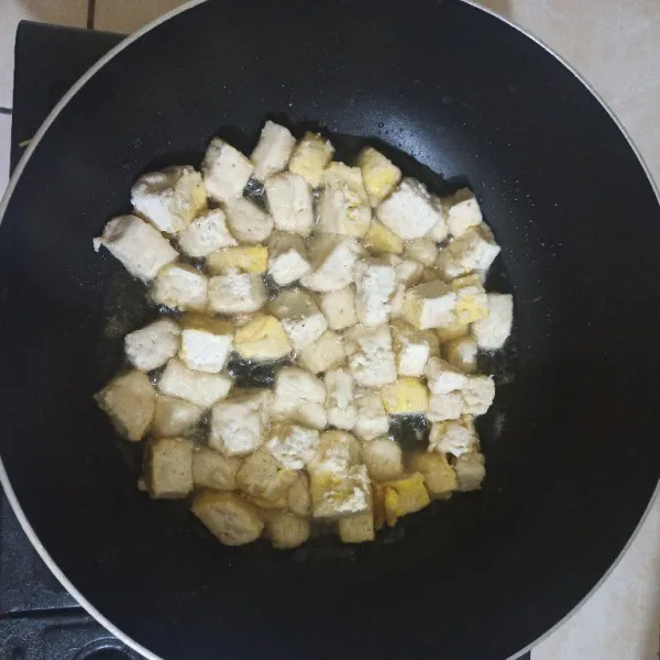 Goreng tahu yang sudah dipotong dadu dan sudah dilumurin dengan tepung serbaguna, hingga kecoklatan.