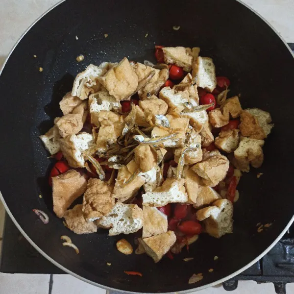 Setelah layu masukkan kulit melinjo dan tahu pong, aduk rata.