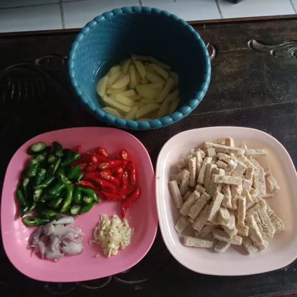 Potong memanjang tempe dan kentang. Iris bawang merah, bawang putih, cabe hijau, dan cabe merah.