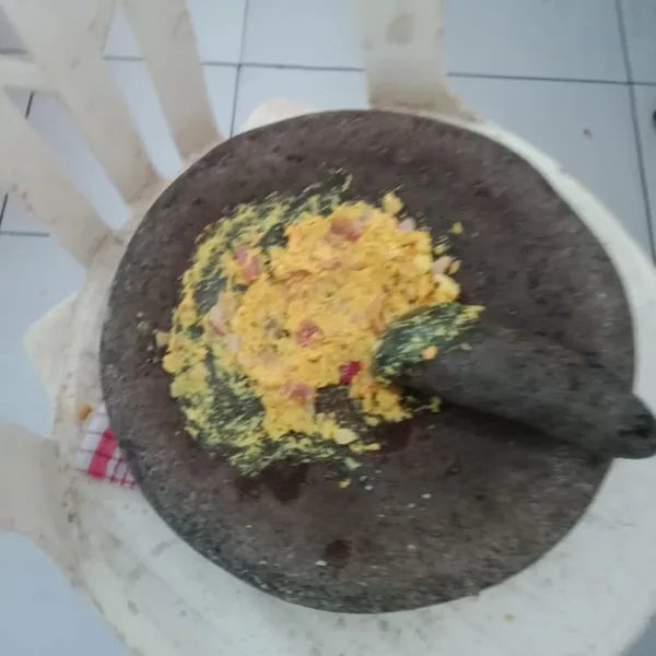 Ulek halus bawang merah, bawang putih, kemiri, kunyit, jahe, dan lengkuas.