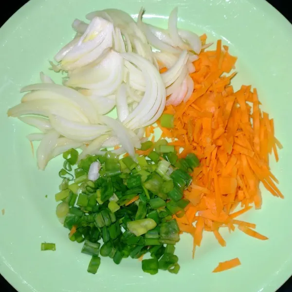 Parut kasar wortel. Kemudian, iris bawang bombay serta daun bawang.