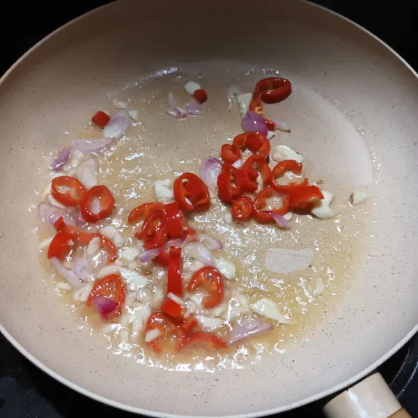Panaskan minyak dari ikan tuna. Lalu tumis bawang merah, bawang putih, dan cabe hingga harum.