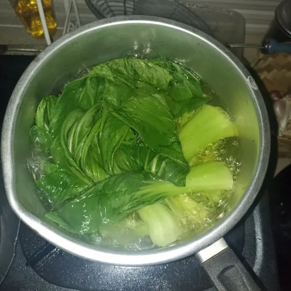 Potong pangkal sawi, cuci, dan rebus selama 3 menit.