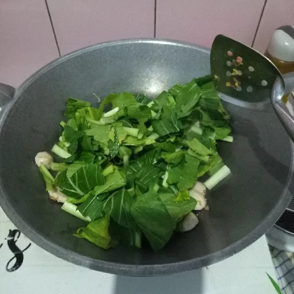 Masukkan caisim, aduk dan masak hingga setengah layu.