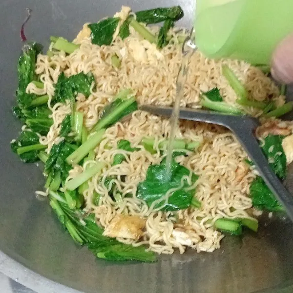Masukkan mie, kemudian tuang air, lalu aduk perlahan hingga rata.