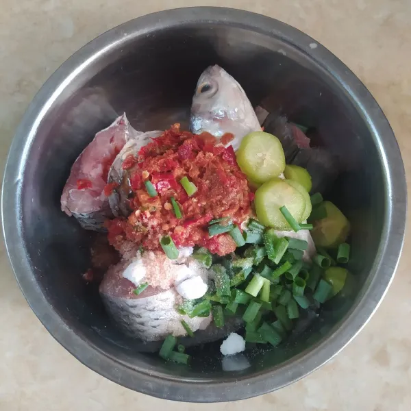 Dalam mangkuk, campur ikan, bumbu halus, belimbing wuluh, daun jeruk, daun bawang, garam, dan gula pasir. Kemudian, aduk rata.