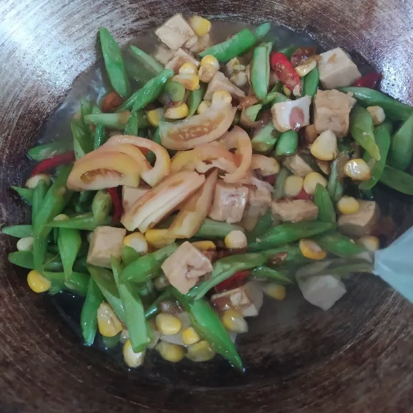 Tambahkan tomat dan tuangkan air. Kemudian, aduk rata. Masak hingga matang meresap dan kuahnya surut.