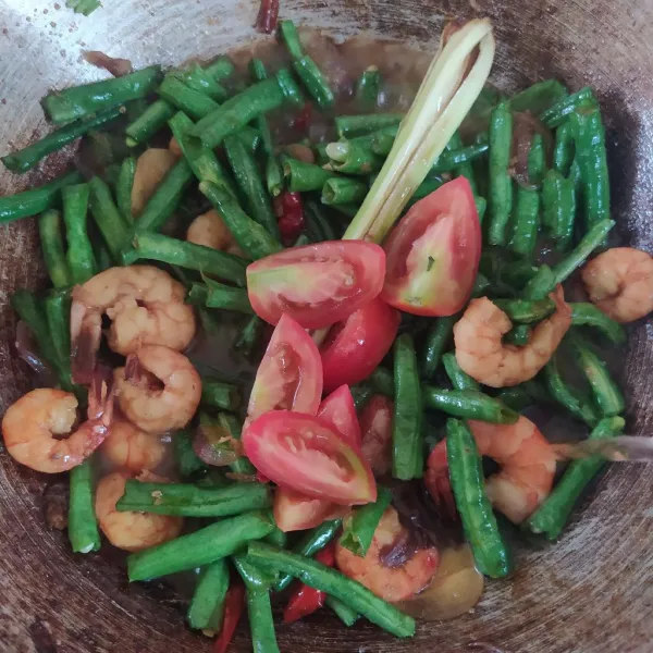 Tuangkan air dan tambahkan tomat, aduk rata. Masak hingga matang, meresap, dan kuahnya surut.