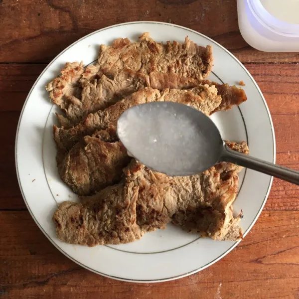 Pindahkan ke wadah saji. Oles seluruh permukaan daging dengan minyak kelapa hingga terendam.