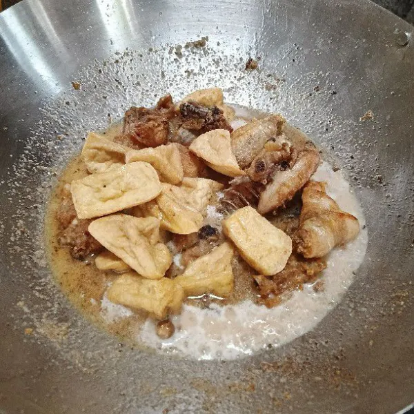 Masukkan ayam dan tahu ke dalam kuali yang sudah dimasukkan santan instan