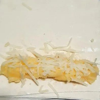 Siapkan kulit pangsit, taruh tape di atas kulit pangsit sesuai selera. Beri taburan keju parut di atasnya, lalu gulung. Untuk lemnya, pakai adonan tepung terigu yang untuk celupan. Lakukan sampai semua selesai.