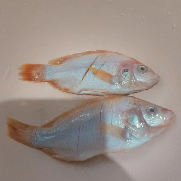 Cuci bersih ikan nila, lumuri dengan garam dan air perasan jeruk nipis, biarkan selama 30 menit.