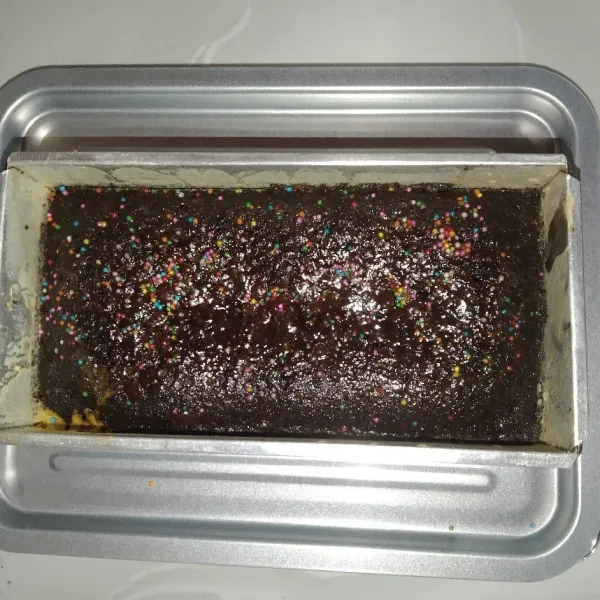 Tuang adonan ke dalam loyang, beri topping choco chips dan meses warna-warni. Lalu, oven selama 30 menit di suhu 180 derajat celsius.