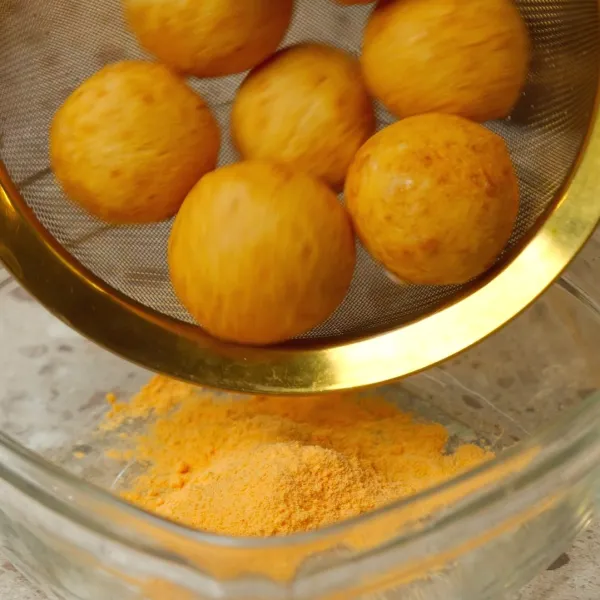 Taburkan cheese balls dengan bubuk keju.