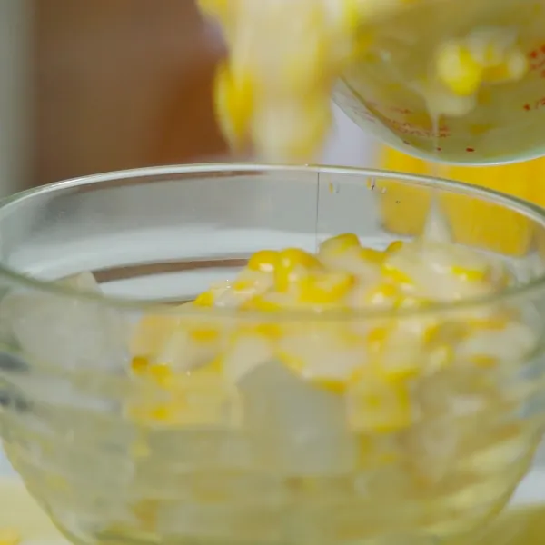 Siapkan gelas lalu tuang jagung, nata de coco, buah kelapa dan susu cair santan.