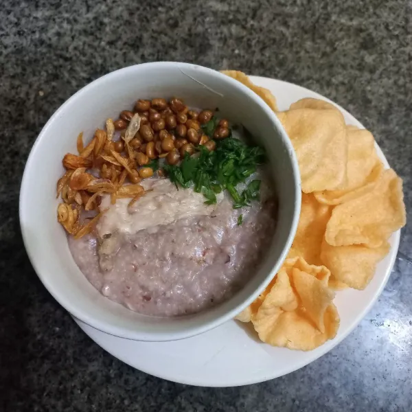 Tuang bubur pada mangkuk, beri pelengkap seperti irisan seledri, bawang goreng, kacang kedelai goreng dan kerupuk.
