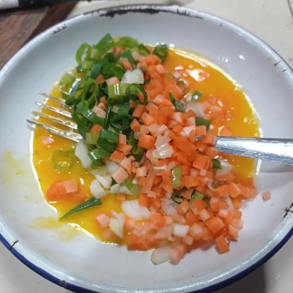 Kocok lepas telur, garam, lada, dan kaldu bubuk. Masukkan wortel, daun bawang, dan bawang bombay. Kemudian, aduk rata.